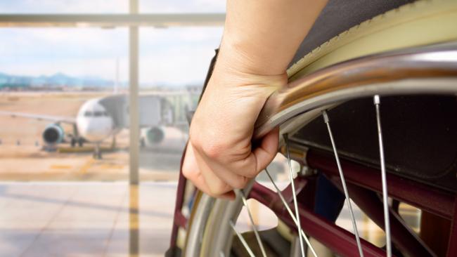 Close up of wheelchair and person looking at airplane outside on runway